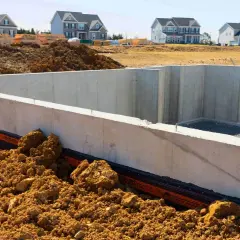 Fundament budowy domu, betonowa ława fundamentowa otoczona ziemią. Zastanawiasz się, ile kosztuje wylanie ławy fundamentowej?