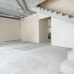 Wnętrze w stanie deweloperskim zamkniętym. Betonowe schody, ściany otynkowane, widoczne instalacje.