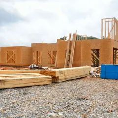 Budowa domu z płyt OSB, stos materiałów budowlanych. Czy płyta OSB może być na deszczu? Tak, ale wymaga zabezpieczenia.