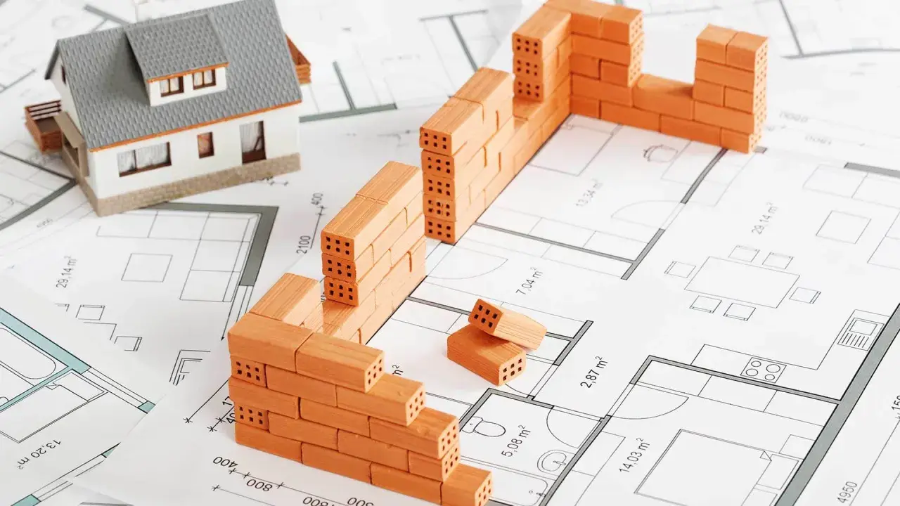 Model domu i mury z cegieł na planie architektonicznym. To wizualizacja, jak zacząć budowę domu.